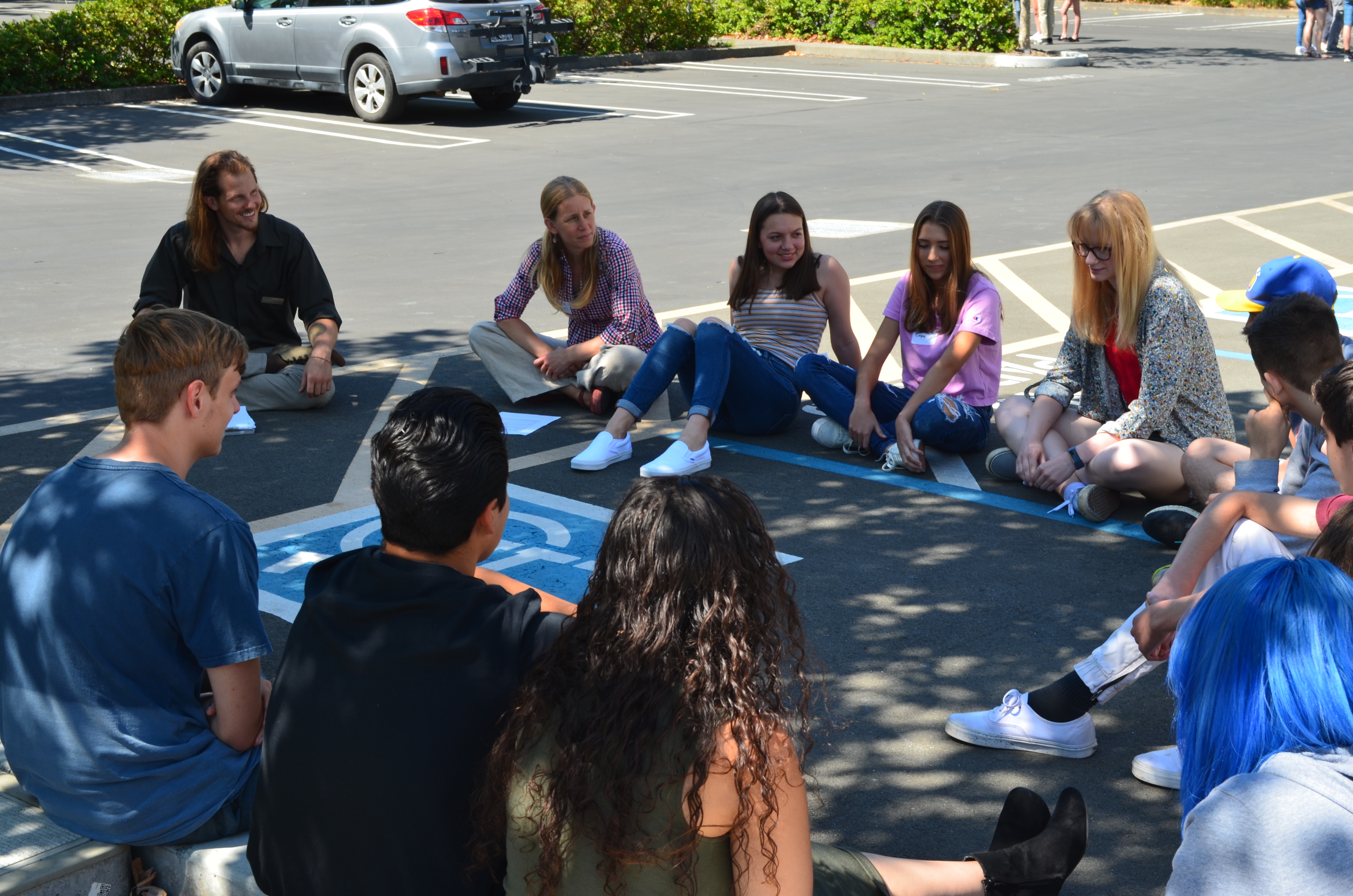 Students from Quest Forward Academy Santa Rosa sit in a circle in the parking lot.