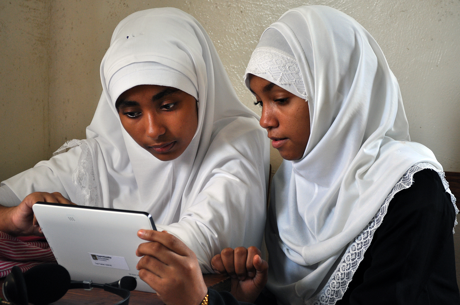 Two Zanzibar students work together in class holding an Opportunity Tablet, provided by Opportunity Education.