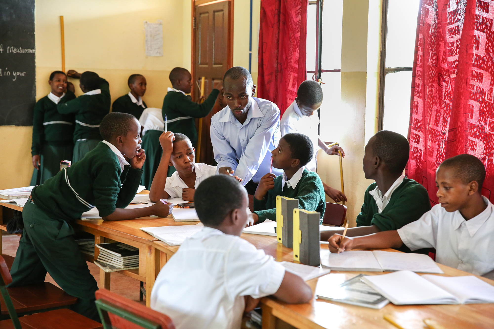 A busy, colorful classroom in Tanzania shows students in small groups learning actively.