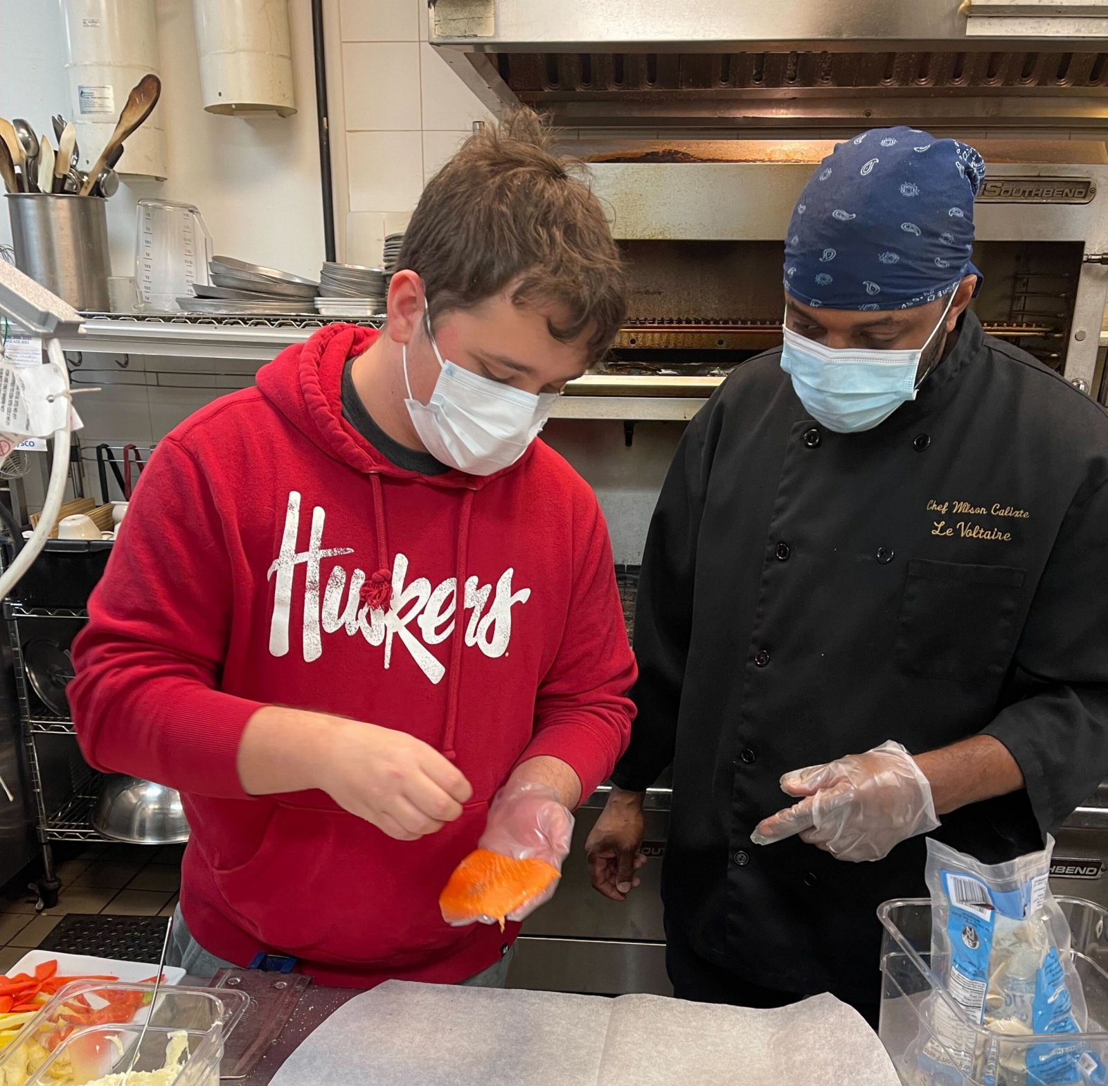 A Quest Forward Academy student works alongside a professional chef in a restaurant kitchen in Omaha.