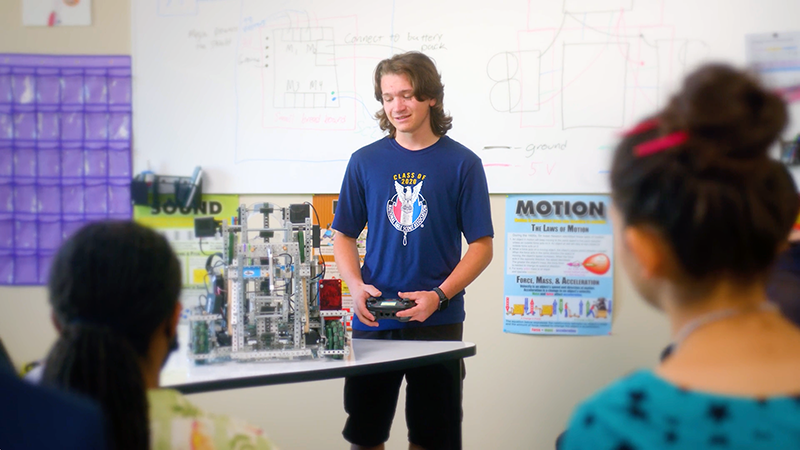 A student demonstrates his robotics project in front of his class in this still from Opportunity Education's video about the importance of active learning.
