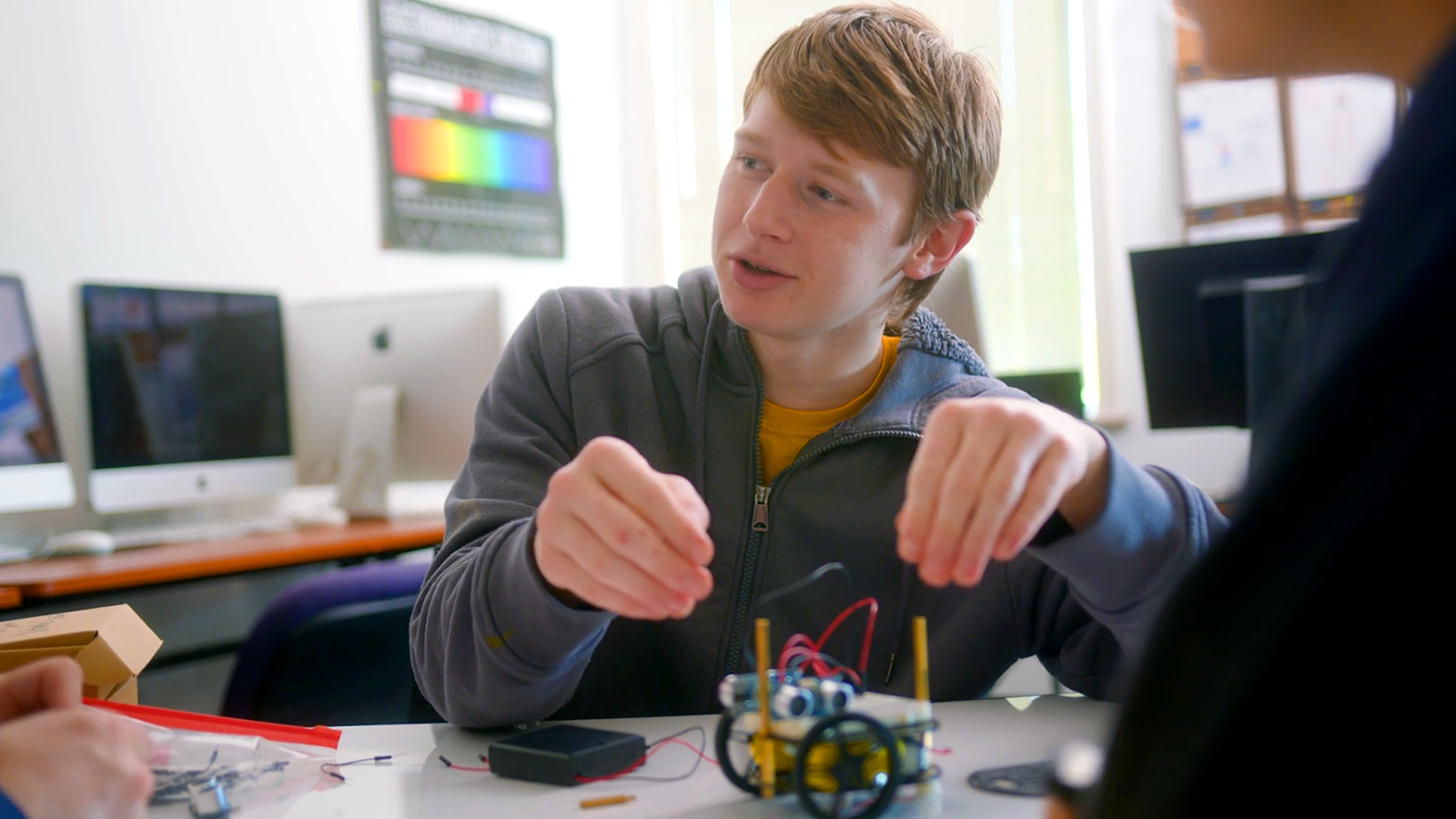 A student collaborates at a table with a robotics project in front of him in this still image from Opportunity Education's video on the power of focused skill development